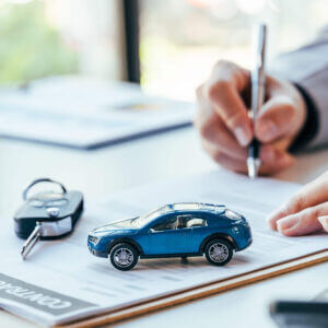 auto loan papers being signed with car keys and toy car