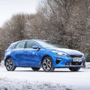 Blue car in the snow, with a license plate reading, "Snow What?"