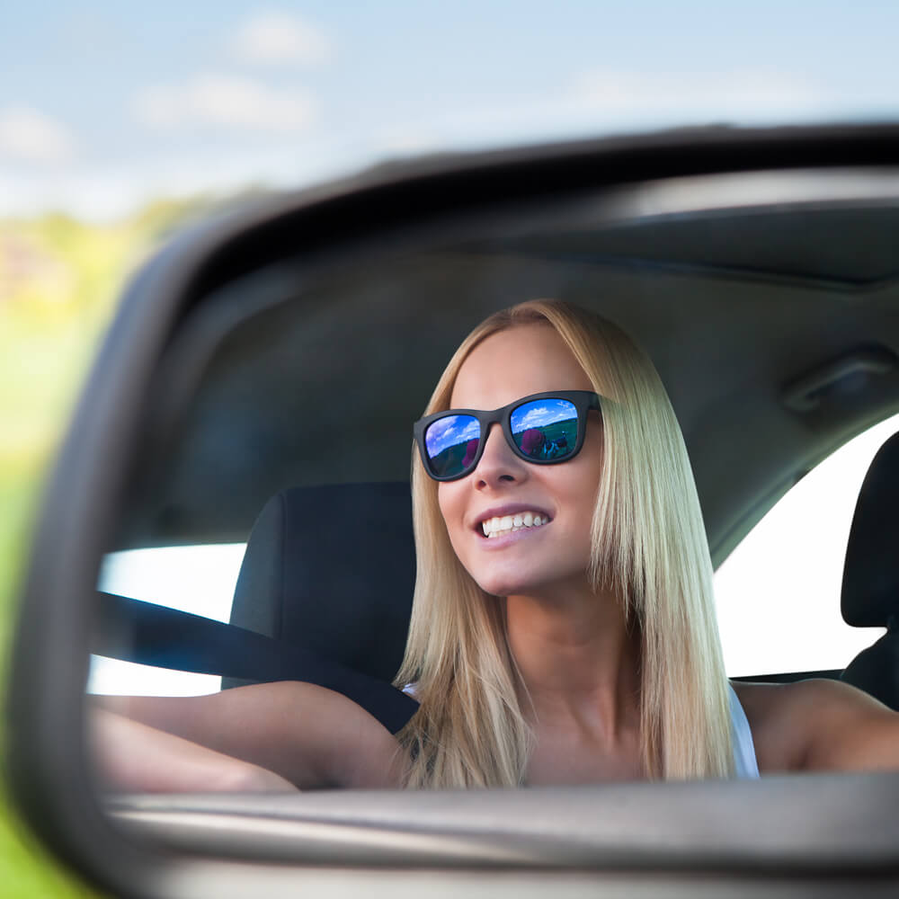 Young student driving in her car looking in the review mirror