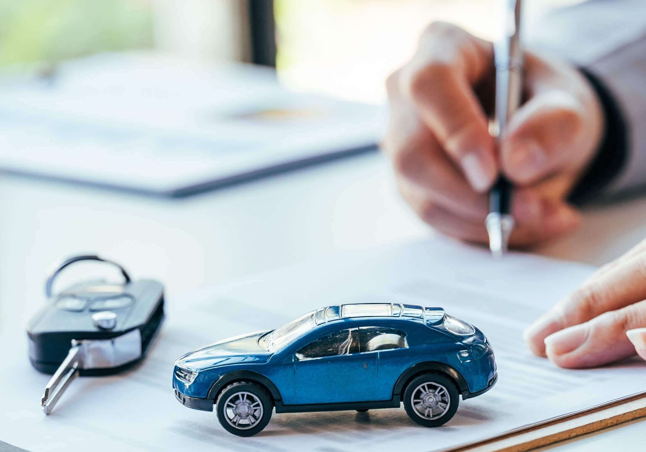 auto loan papers being signed with car keys and toy car