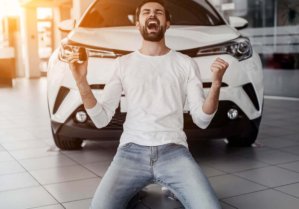 Man on his knees shouting for joy after buying a car
