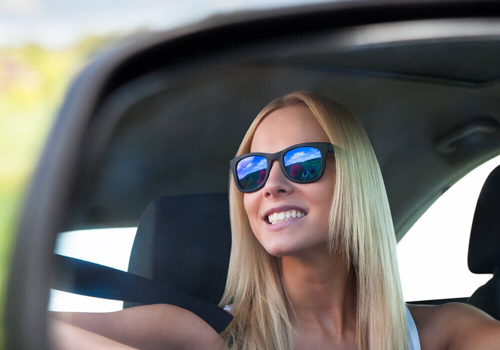 Young student driving in her car looking in the review mirror